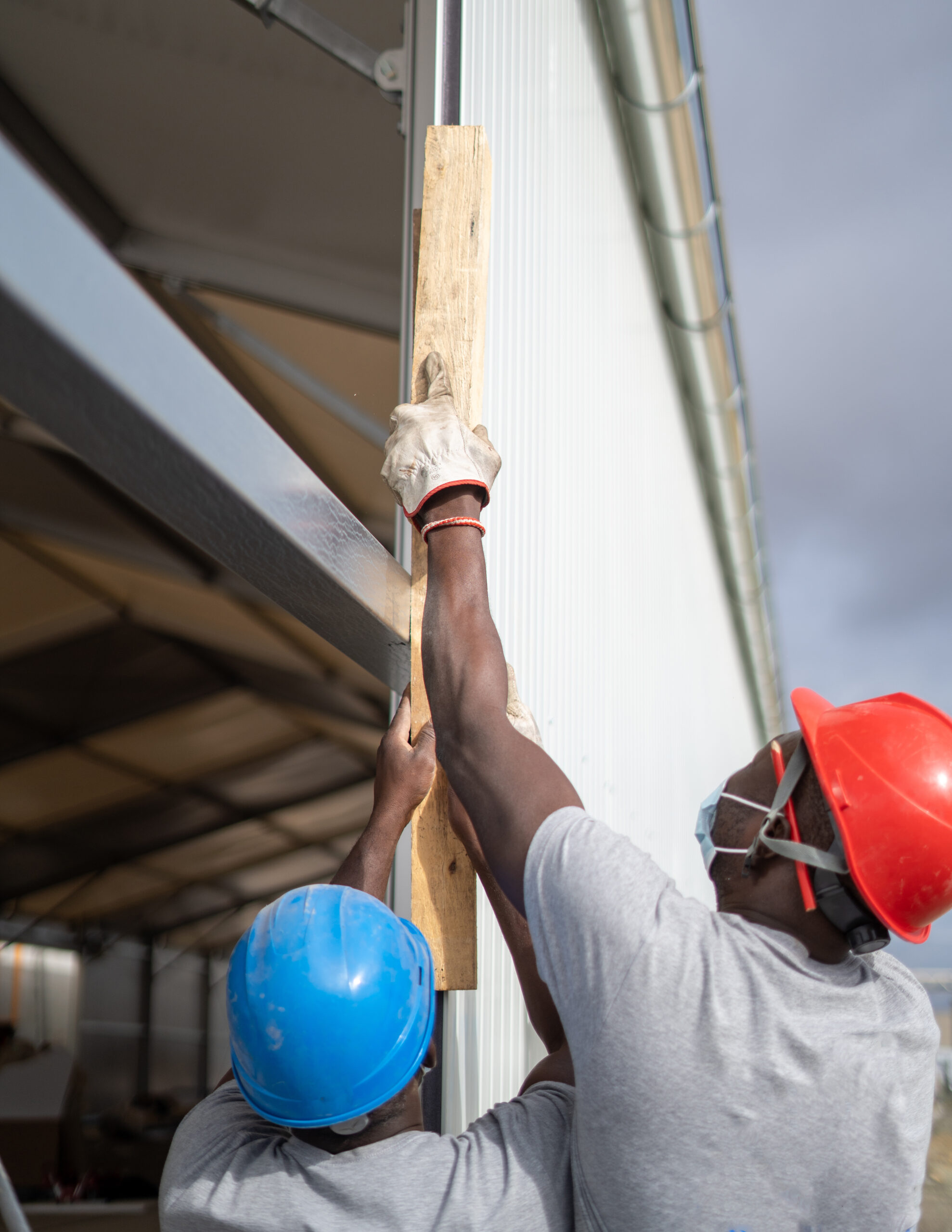 afro american builders wearing helmets and face masks while measuring the wall